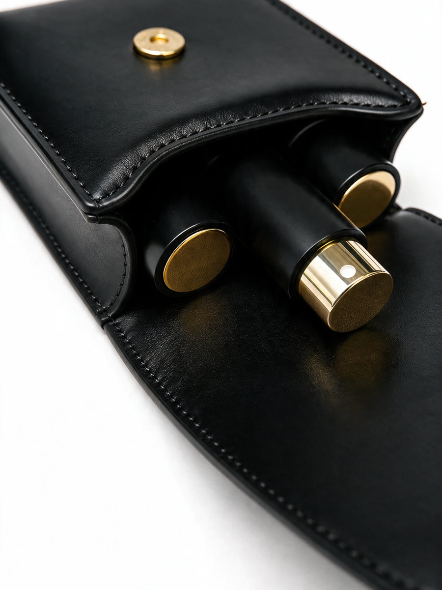 Close up of the black travel pouch flap with black and gold perfume bottles inside