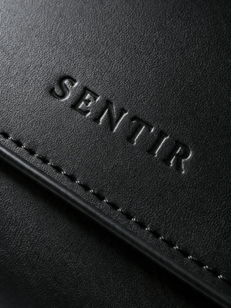 Embossed Sentir logo on black vegan leather travel pouch