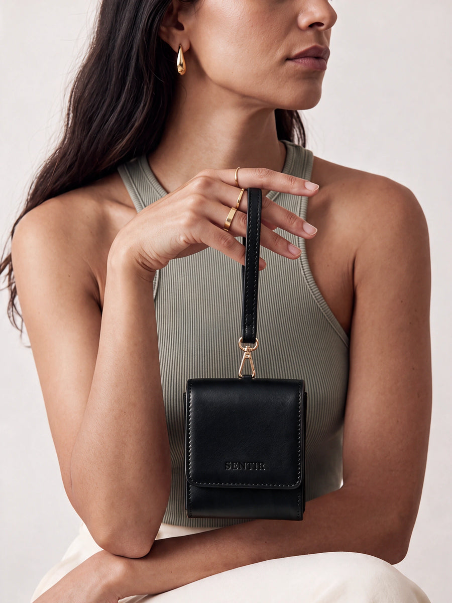 Woman holding the black Sentir travel pouch by its wrist strap