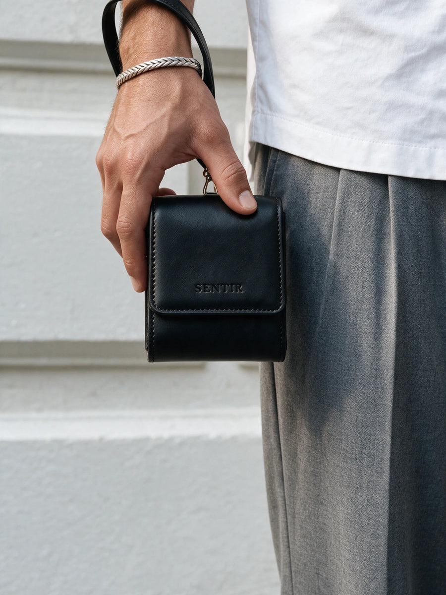 Man carrying the black Sentir travel pouch by its wrist strap
