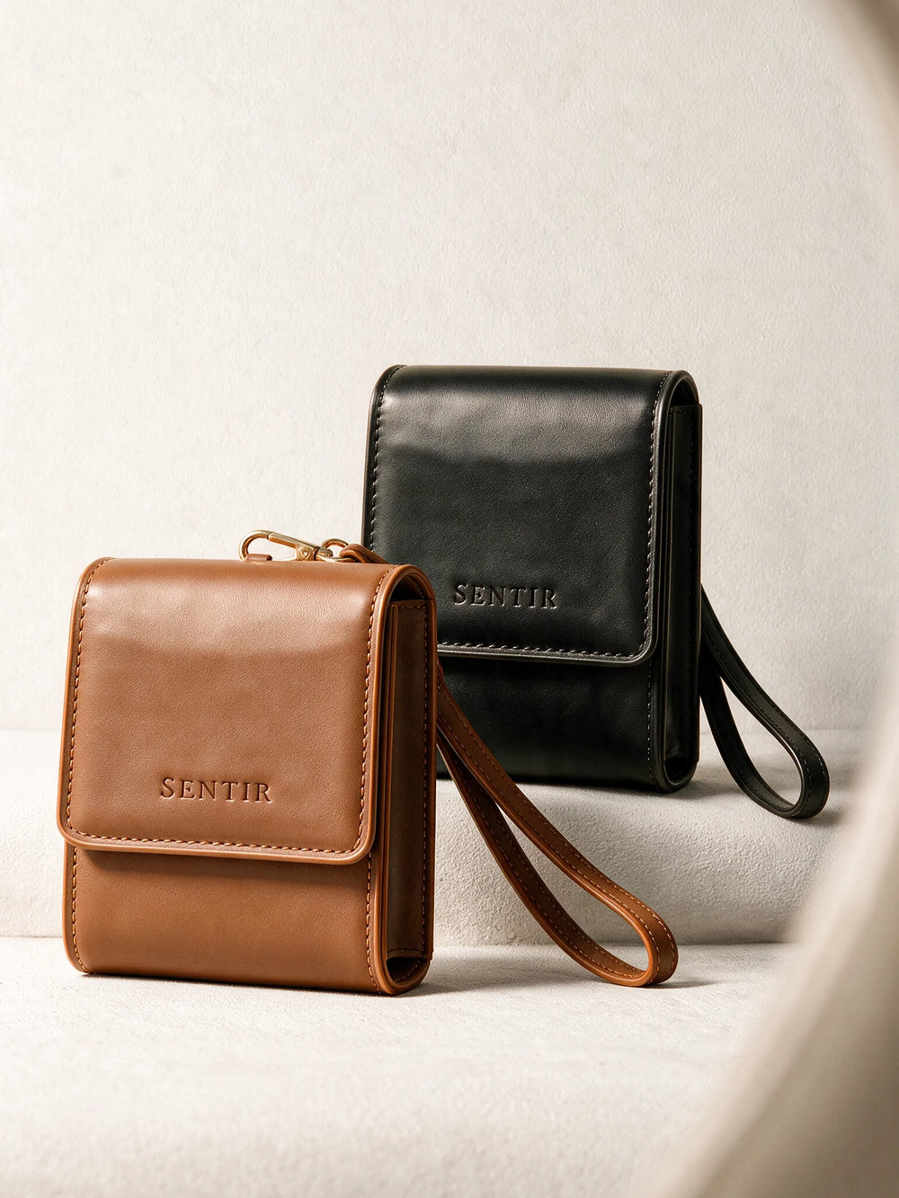 Sentir travel pouch in brown and black vegan leather shown side by side