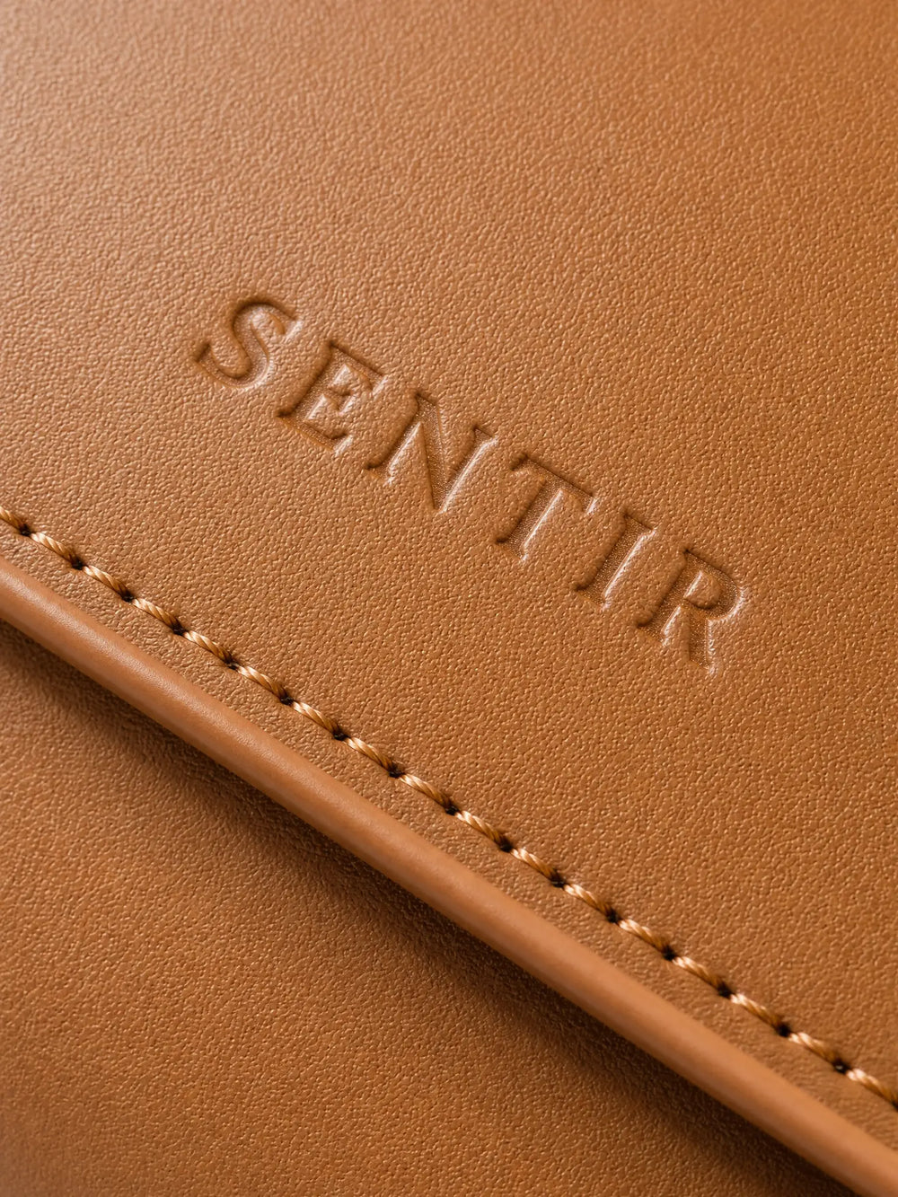 Embossed Sentir logo on brown vegan leather travel pouch