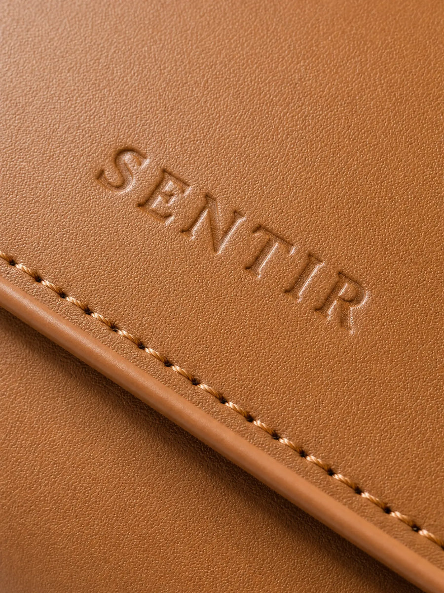 Embossed Sentir logo on brown vegan leather travel pouch
