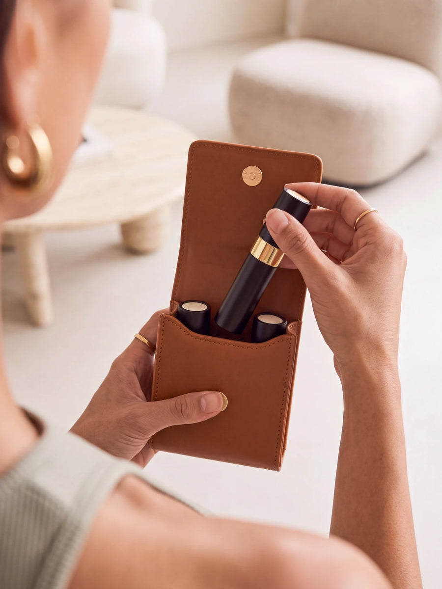 Woman taking a 10 ml perfume bottle out of the open brown Sentir travel pouch